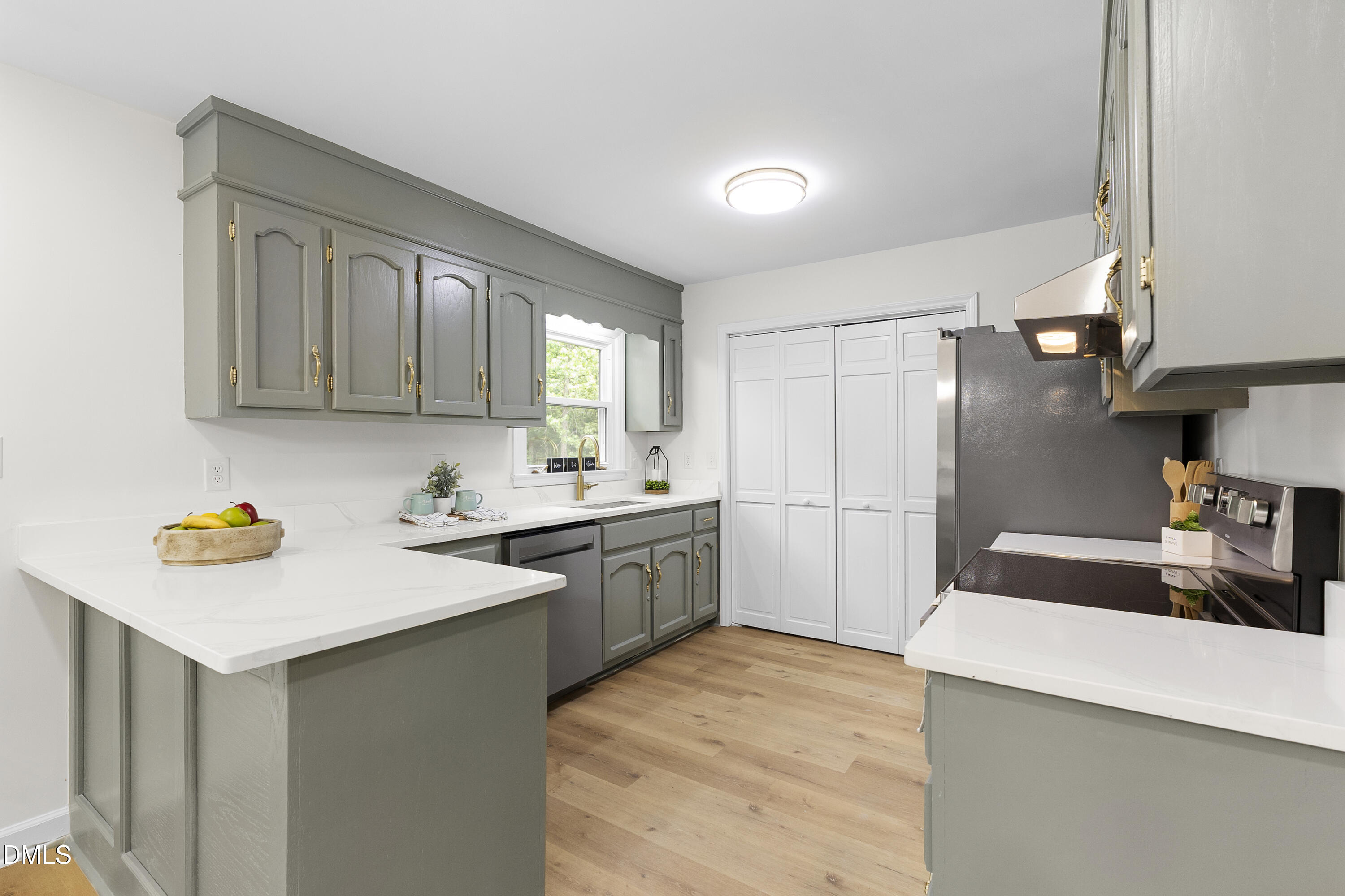 2168 Lakewood Falls Road Goldston, NC 27252 - Photo 12 of 30 a kitchen with a sink dishwasher a stove and white cabinets with wooden floor
