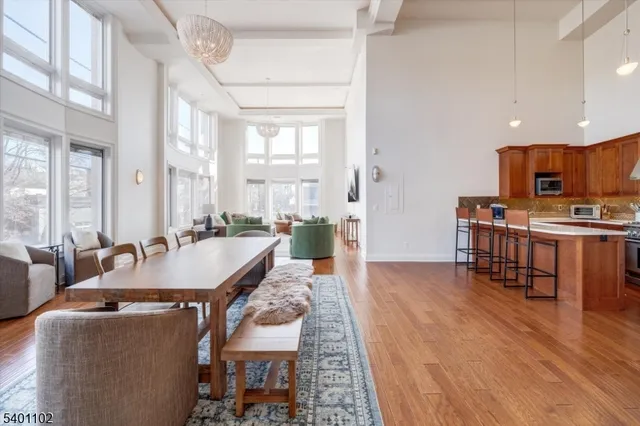 a large living room with stainless steel appliances kitchen island granite countertop a table chairs and a refrigerator