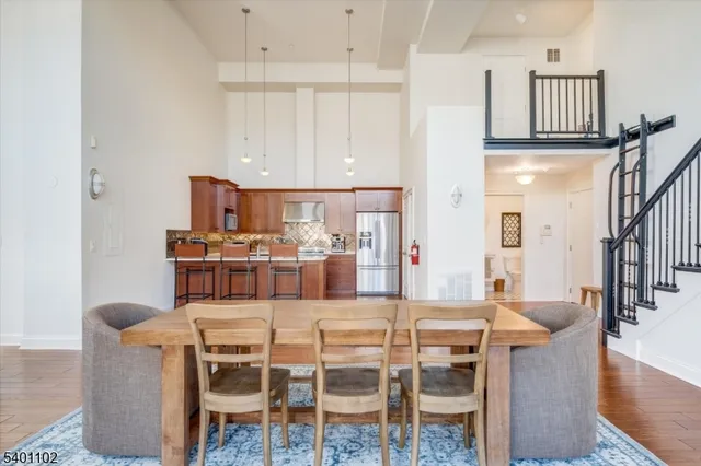 a kitchen with stainless steel appliances kitchen island granite countertop a dining table chairs and a refrigerator