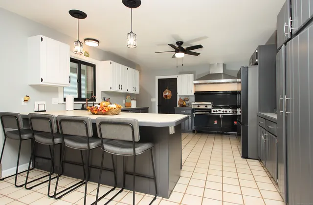 a kitchen with stainless steel appliances kitchen island granite countertop a sink a stove a refrigerator and island with wooden floor