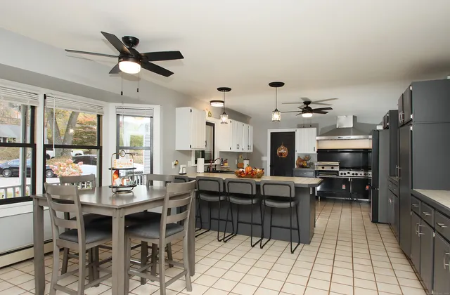 a kitchen with stainless steel appliances kitchen island granite countertop a table chairs and a view of living room