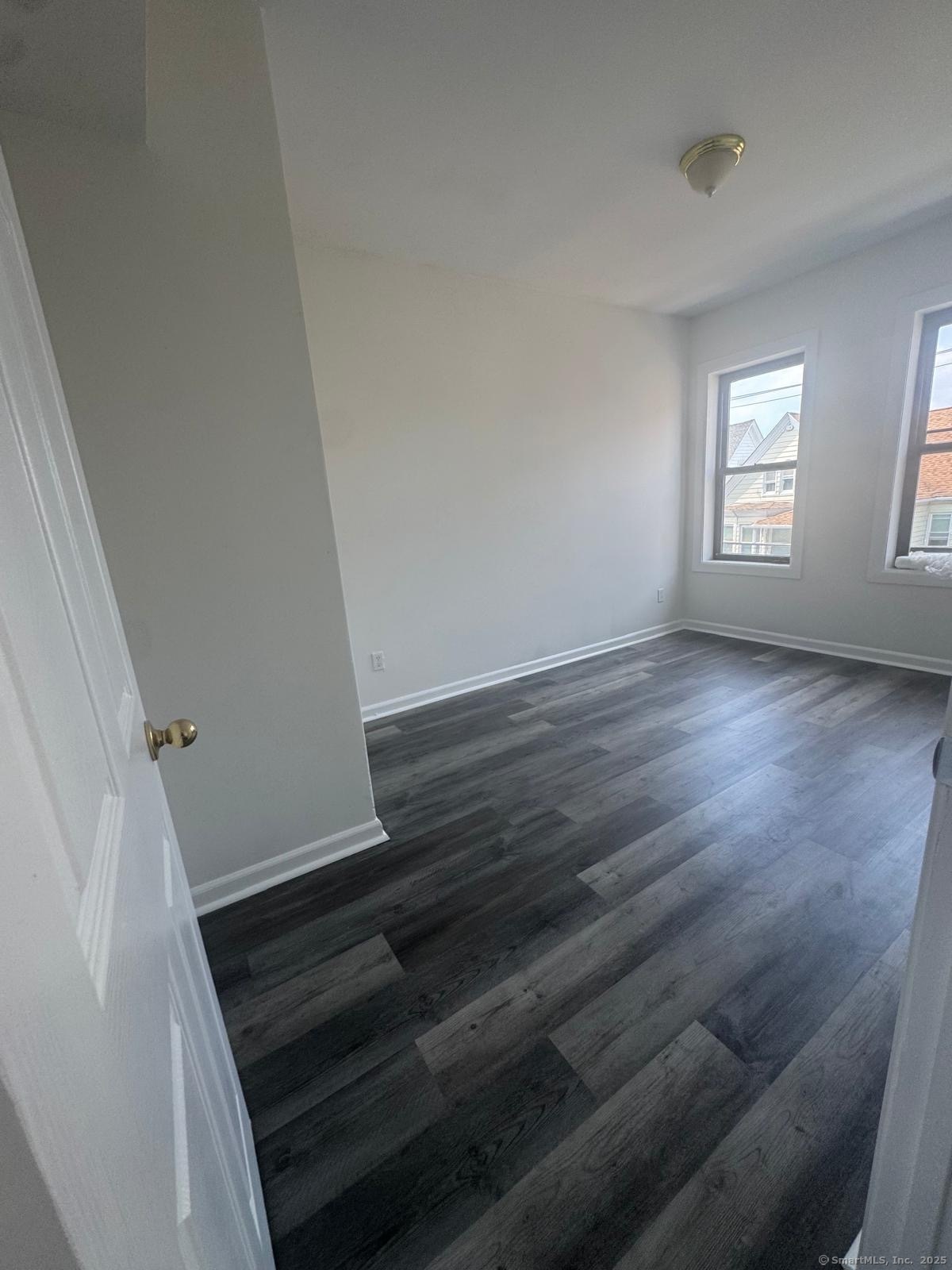 1071 Pembroke Street, Unit 3E Bridgeport, CT 06608 - Photo 2 of 3 a view of an empty room with wooden floor and stairs