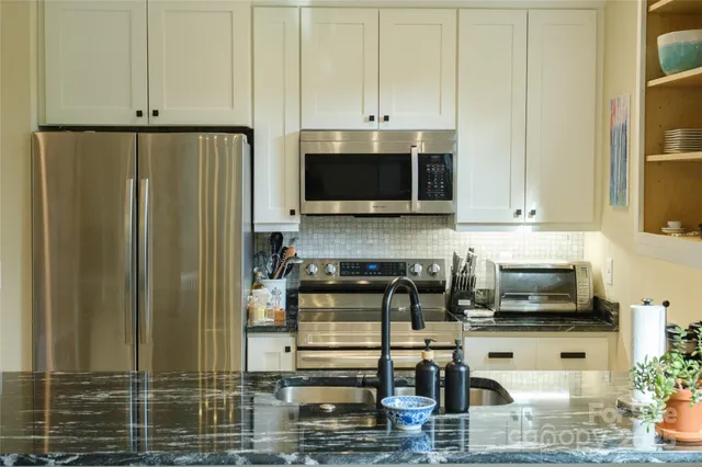 a kitchen with stainless steel appliances granite countertop a refrigerator a stove and a microwave