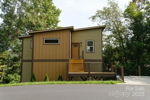 a view of a house with a small yard and large tree