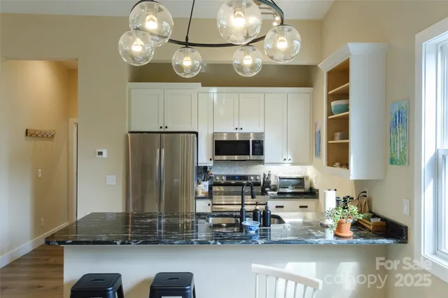 a kitchen with kitchen island granite countertop stainless steel appliances a stove refrigerator and microwave