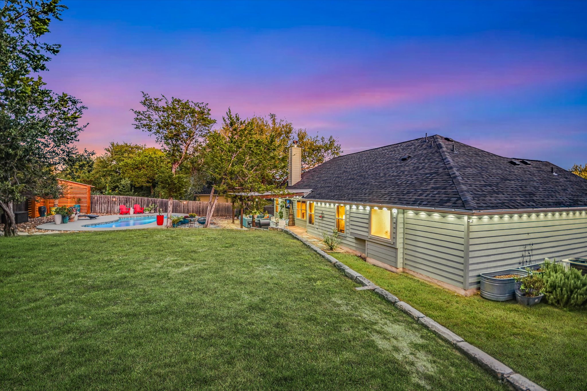 36 Ridgewood Circle Wimberley, TX 78676 - Photo 28 of 30 A spacious green lawn sits beside the classic siding exterior and backyard swimming pool.