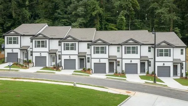 a view of multiple houses with a big yard and large trees