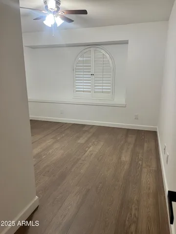 en empty room with wooden floor and fan