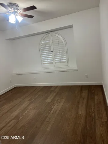 en empty room with wooden floor fan and window