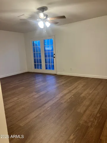a view of an empty room with window and chandelier fan
