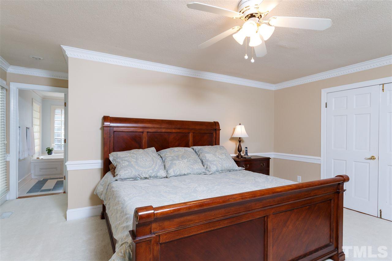 4921 Springwood Drive Raleigh, NC 27613 - Photo 12 of 25 a bedroom with a bed and a chandelier