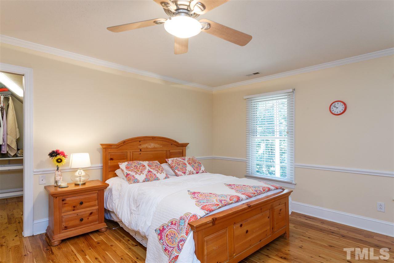 4921 Springwood Drive Raleigh, NC 27613 - Photo 18 of 25 a bedroom with a bed and a chandelier