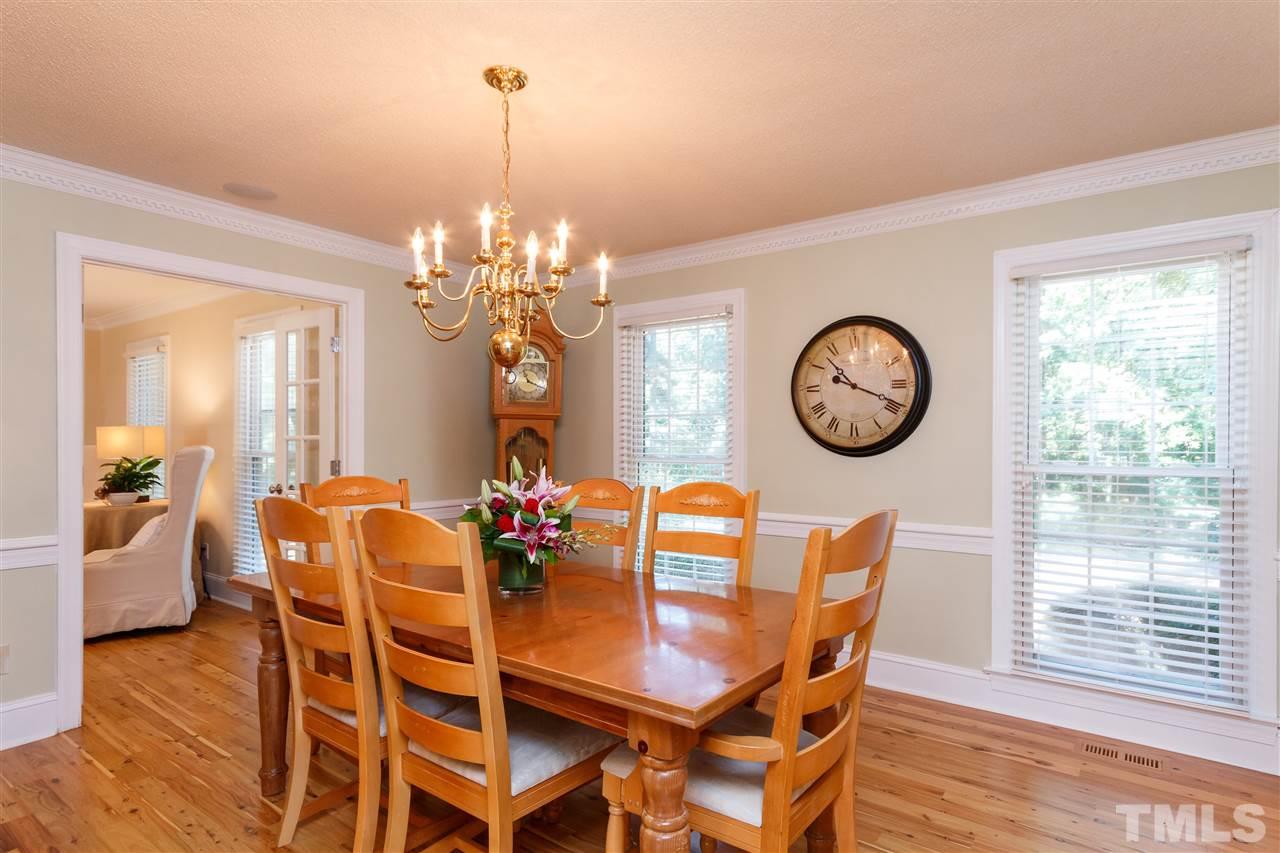 4921 Springwood Drive Raleigh, NC 27613 - Photo 3 of 25 a dining room with furniture a chandelier and wooden floor