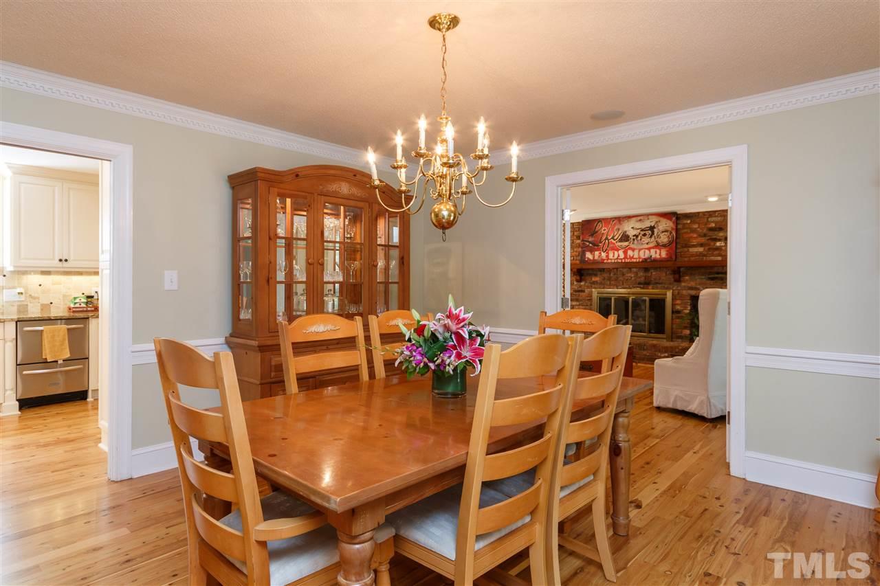 4921 Springwood Drive Raleigh, NC 27613 - Photo 4 of 25 a dining room with furniture a chandelier and wooden floor