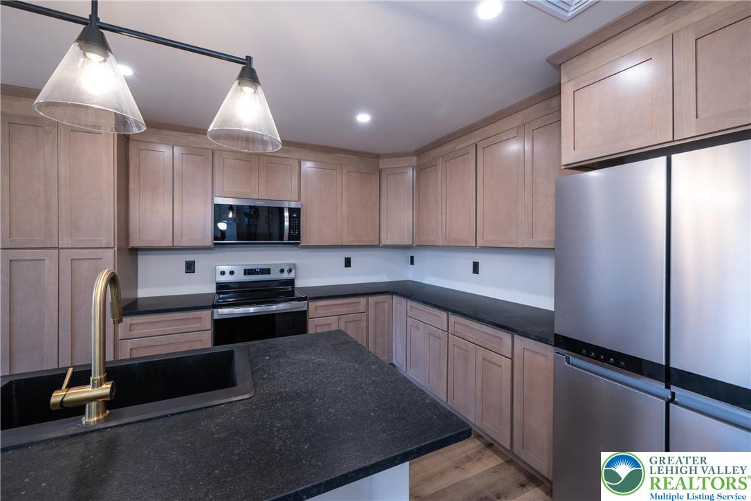 111 Main Street Glendon, PA 18042 - Photo 6 of 33 a kitchen with stainless steel appliances kitchen island granite countertop a refrigerator a sink dishwasher a stove and a microwave oven