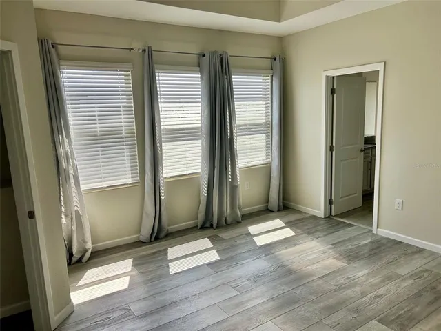 an empty room with wooden floor and windows