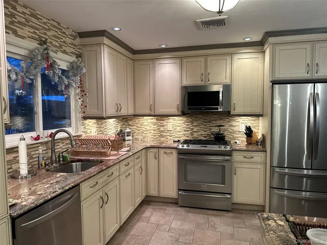 a kitchen with granite countertop a sink cabinets and stainless steel appliances