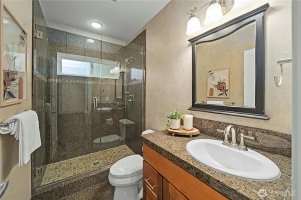 a bathroom with a granite countertop sink toilet and shower