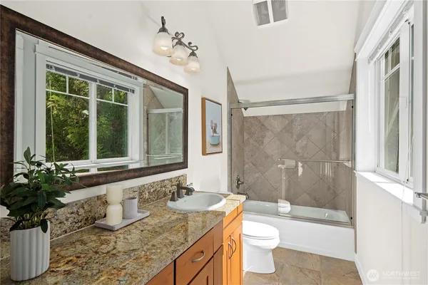 a bathroom with a granite countertop sink a large mirror and a bathtub