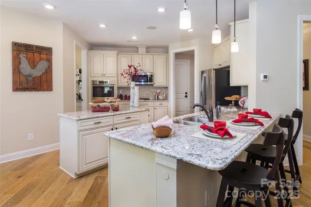 a kitchen with granite countertop kitchen island stainless steel appliances sink refrigerator and dining table