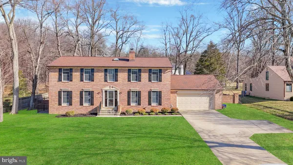 a front view of a house with garden and trees