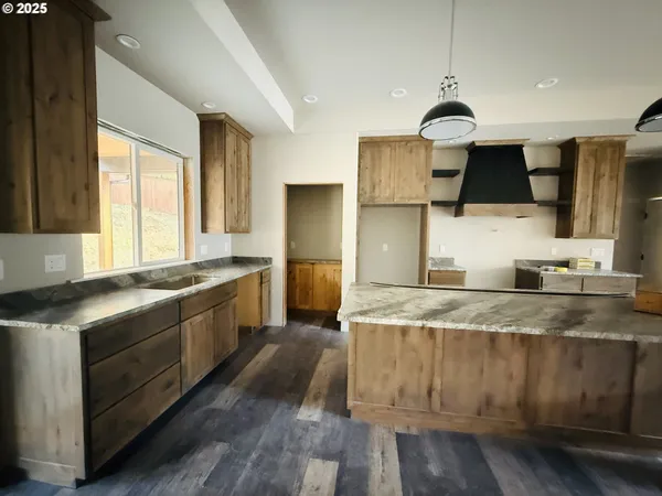 a kitchen with stainless steel appliances granite countertop a sink a stove and a wooden floors