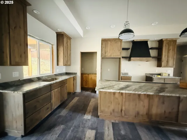 a kitchen with stainless steel appliances granite countertop a sink a stove and a wooden floors