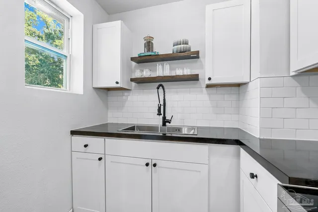 a kitchen with granite countertop a sink a window and cabinets