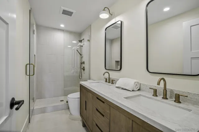 a bathroom with a double vanity sink double mirror and shower