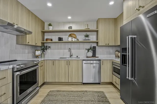 a kitchen with stainless steel appliances granite countertop a sink a stove a refrigerator and cabinets