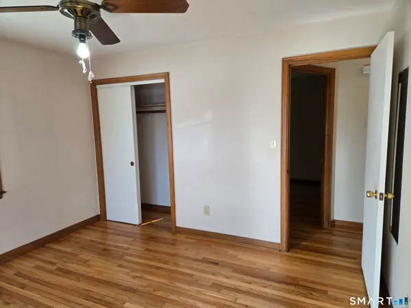 a view of an empty room with wooden floor and a mirror