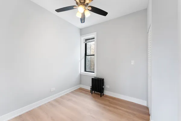 an empty room with a window and a ceiling fan