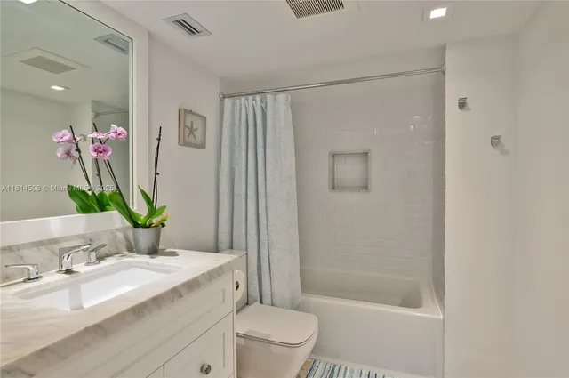 a bathroom with a granite countertop sink a toilet and shower