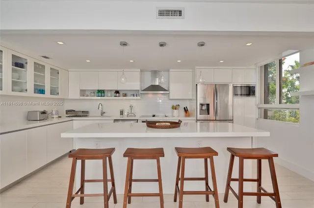 a kitchen with stainless steel appliances granite countertop a table chairs sink and cabinets