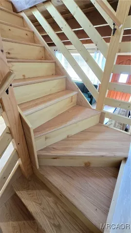a view of an empty room with wooden floor and furniture