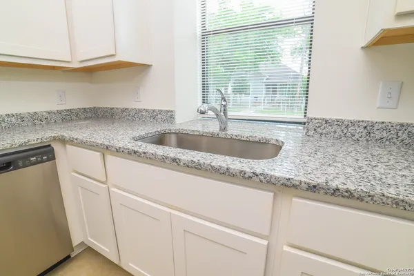 a kitchen with granite countertop a sink and a white wooden cabinets