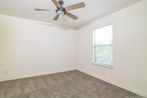 an empty room with a window and a fan