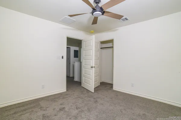 an empty room with a ceiling fan and carpet