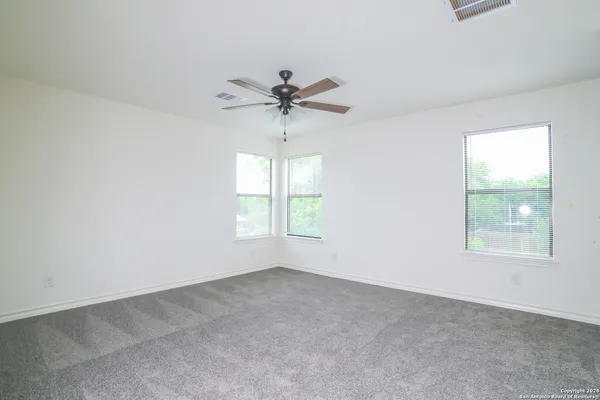 an empty room with windows and fan