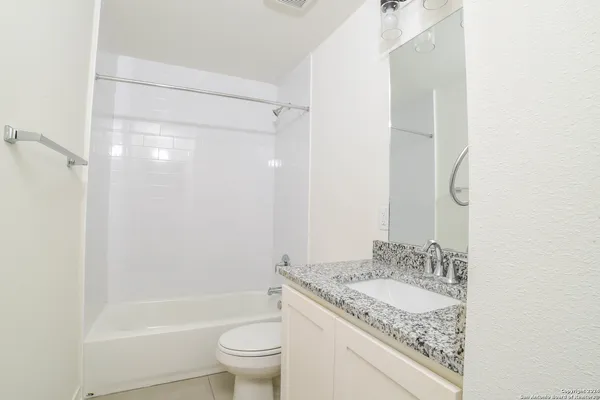 a bathroom with a granite countertop sink toilet and shower