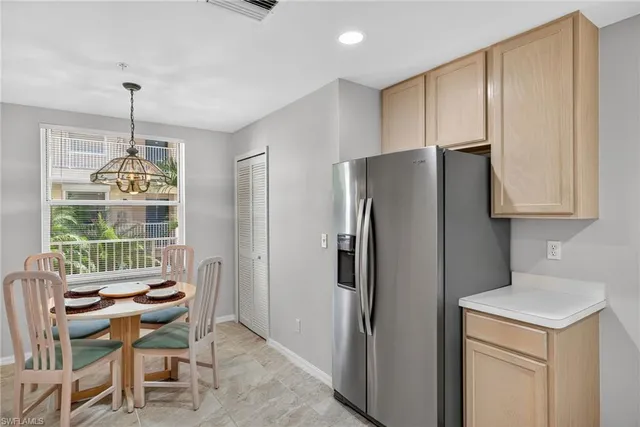 a kitchen with stainless steel appliances a refrigerator a table and chairs in it