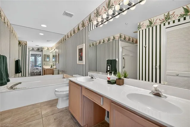 a bathroom with a double vanity sink a toilet and a large mirror