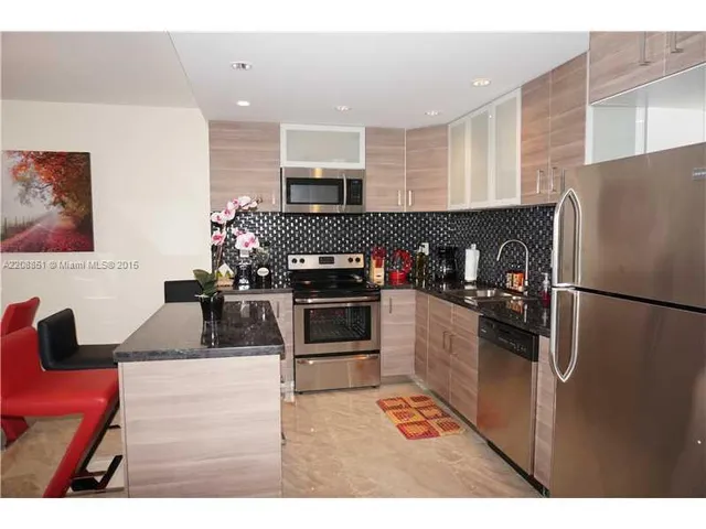 a kitchen with stainless steel appliances kitchen island granite countertop a refrigerator and a stove top oven