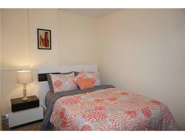 a bedroom with a bed and a lamp on dresser