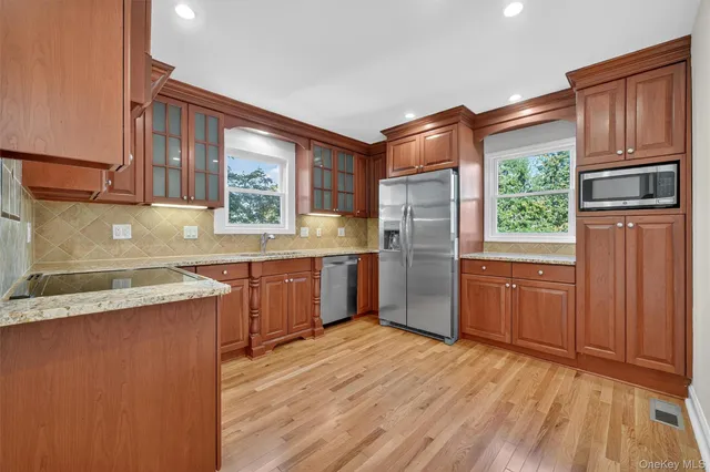 a kitchen with stainless steel appliances granite countertop a refrigerator a sink dishwasher a oven with wooden cabinets and floors