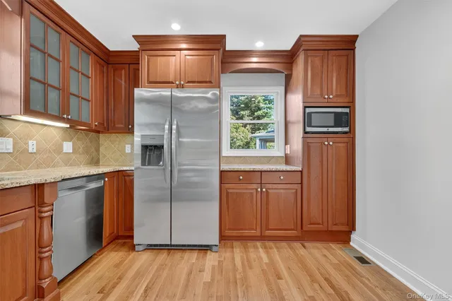 a kitchen with stainless steel appliances granite countertop a refrigerator a sink and wooden cabinets