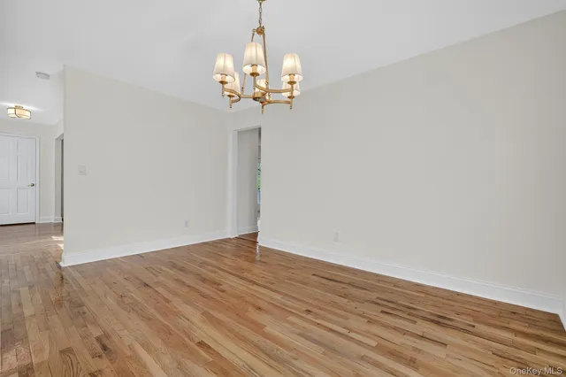 a view of a chandelier in big room with wooden floor