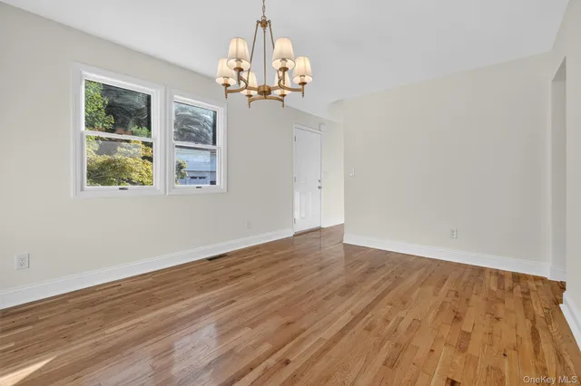 a view of a room with wooden floor chandelier and windows