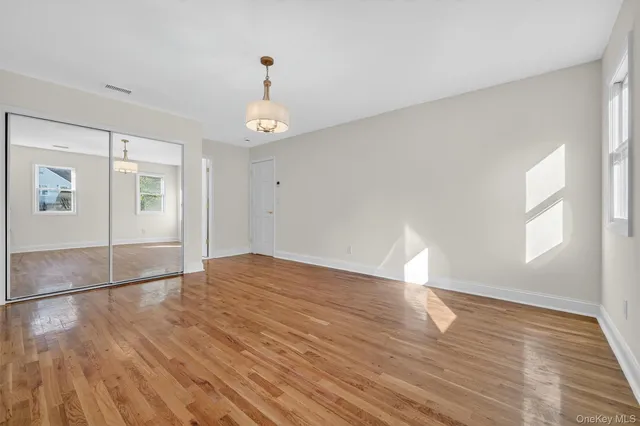 a view of empty room with wooden floor and window