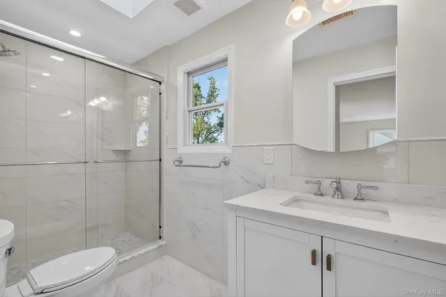a bathroom with a shower sink vanity mirror and toilet